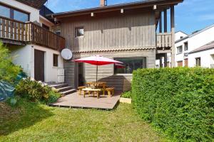 a patio with a table and a red umbrella at Bargkass - Vue montagne et piscine in La Bresse