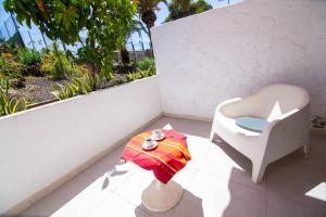 a white chair and a table on a balcony at Chaparal Design Apartment in Costa Del Silencio