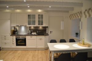 een keuken met witte kasten en een tafel met stoelen bij Haus Boldix Whg 1 Aruba in Boldixum