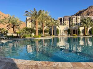 uma grande piscina com palmeiras e edifícios em aladnan Chalet alraha village em Aqaba