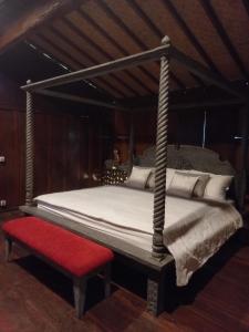 - un lit à baldaquin avec un banc rouge dans une chambre dans l'établissement Gladak Mesari, à Keramas