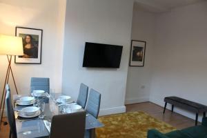 a dining room with a table and a flat screen tv at Grove Bay Inn Home in Leeds - Harehills in Leeds