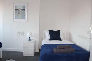 a bedroom with a bed with a blue blanket at Grove Bay Inn Home in Leeds - Harehills in Leeds