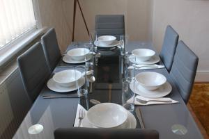 uma mesa de vidro com cadeiras e pratos em Grove Bay Inn Home in Leeds - Harehills em Leeds