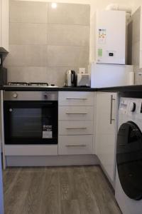 uma cozinha com um fogão e um micro-ondas em Grove Bay Inn Home in Leeds - Harehills em Leeds
