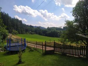 un parque infantil en un campo junto a una valla en Apartmán u lesa, en Jívka