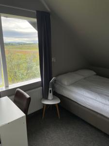 a bedroom with a bed and a chair and a window at Guesthouse Bitra B&B in Selfoss