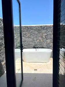 a bath tub in a bathroom with a stone wall at Villa Lavayarena in La Oliva