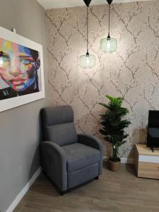 a living room with a chair and a painting at Urbanlux Recinto Ferial in Albacete