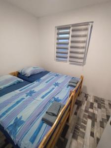 a bedroom with a bed with blue sheets and a window at Kuća za odmor Drina in Zvornik