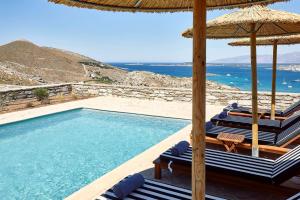 - une piscine avec des chaises et un parasol et l'océan dans l'établissement Platinum Paros Villa - Villa Azure - 5 Bedrooms - Sea Views & Private Pool - Naoussa, à Kolympithres
