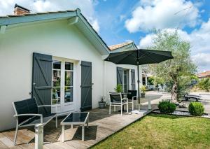 un patio con sillas y una sombrilla frente a una casa en Chambre avec salle de bain privée de la Canopée de Mios, en Mios