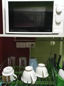 a kitchen counter with three cups and a microwave at Smile Capsule Hostel in Chiang Mai