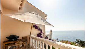 einen Balkon mit einem weißen Sonnenschirm und Meerblick in der Unterkunft Petit Paradis sur la Mer in Saint-Raphaël