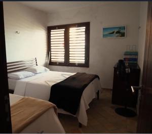 1 dormitorio con 2 camas y ventana en Casa Paraiso, en Maxaranguape