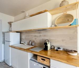 a kitchen with white cabinets and a wooden counter top at Petit Paradis vue Mer- Plage et calanques a 3 mn in Saint-Raphaël
