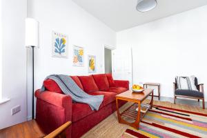 uma sala de estar com um sofá vermelho e uma mesa em Spacious 3BR House, 8 min Kensal Green, NW London em Londres