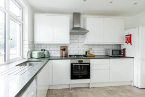 a white kitchen with white cabinets and a sink at Spacious 3BR House, 8 min Kensal Green, NW London in London