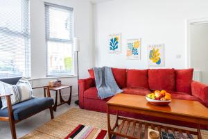 uma sala de estar com um sofá vermelho e uma taça de fruta numa mesa em Spacious 3BR House, 8 min Kensal Green, NW London em Londres