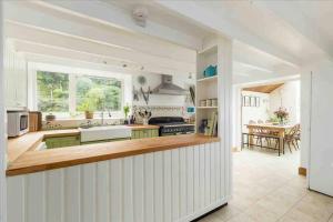 uma cozinha branca com um balcão e uma mesa em Shannobank farmhouse em Duns