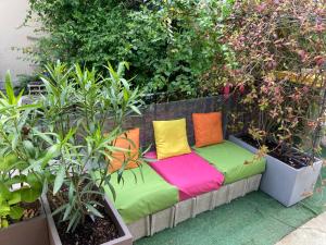 a couch with colorful pillows sitting on a patio at Une chambre chez nous, à 12 minutes de Paris in Malakoff