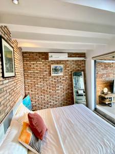 a bedroom with a bed and a brick wall at The Palmian City Center Serviced Apartment in Ho Chi Minh City