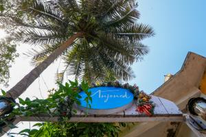 a sign for a hotel with a palm tree in the background at Anjoned Hostel & Cafe in Anjuna