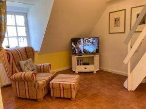 Strandperle Herrenhof في Wrixum: غرفة معيشة مع كرسيين وتلفزيون