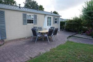 a patio with a table and chairs in front of a house at Kustverhuur, Groede, Paarlhof 37 in Groede +8 photos