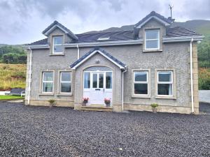 ein Haus mit einer weißen Tür auf einer Kieseinfahrt in der Unterkunft GlenVista Holiday Accommodation in Glenariff