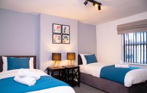 dwa łóżka w pokoju niebiesko-białym w obiekcie Comfortable Stay for 6, Charming 3-Bedrooms near Gloucester Quays with Parking w mieście Hempstead