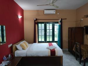 a bedroom with a bed and a red wall at Wild Horizons Guest House in Sauraha