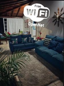 a living room with blue couches and a sign free wifi operator at Casa aconchegante em bairro nobre da cidade Paraty in Paraty