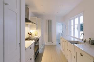 cocina blanca con fregadero y fogones en Beautiful house, Cirencester centre, parking, en Cirencester