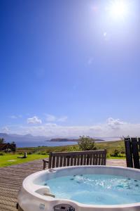 a hot tub sitting on a deck with a bench at Stac Polly Lodge in Achiltibuie