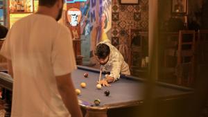 a man playing billiard in a pool table at Anjoned Hostel & Cafe in Anjuna