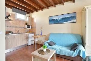 a living room with a blue couch and a kitchen at Viviendas El Pescador - Timón in El Golfo