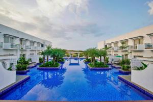 uma grande piscina com palmeiras e edifícios em Pramod Lands End Resort, a member of Radisson Individuals em Gopalpur