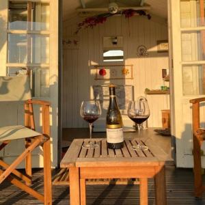 a bottle of wine on a wooden table with two wine glasses at The Stables @ The Forge Cronk Y Voddy in Saint Johns