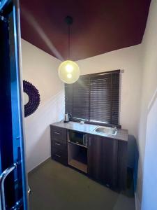 una pequeña cocina con fregadero y ventana en The Orange Door Annex 2, en Lekki
