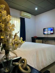- une chambre avec un lit et un vase de fleurs sur une table dans l'établissement The Orange Door Annex 2, à Lekki