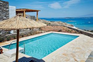 a swimming pool with a straw umbrella and the ocean at Platinum Paros Villa - 2 Bedrooms - Villa Turquoise - Sea View & Private Pool - Naoussa in Kolympithres