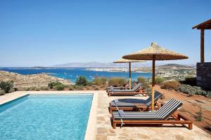 a swimming pool with two chairs and an umbrella at Platinum Paros Villa - 2 Bedrooms - Villa Turquoise - Sea View & Private Pool - Naoussa in Kolympithres