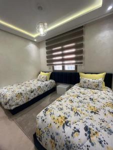 a bedroom with two beds in a room at bon vivant, calme, famille, équipé, clim, TV, parking, parc, agadir, 7 personnes, stylé, wifi portable in Agadir