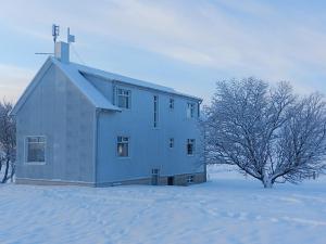 uma casa num campo coberto de neve com uma árvore em Farmhouse Meiri-Tunga 1 em Hella