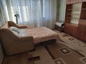 een slaapkamer met een bed, een stoel en een raam bij Dacia in Chişinău