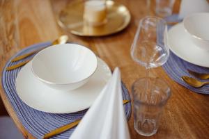 - une table en bois avec des assiettes blanches et un verre de vin dans l'établissement Exklusive Ferienwohnung Arthur, à Zeitz