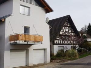 ein weißes Haus mit zwei Garagentüren und einem Balkon in der Unterkunft Ferienwohnung Haus Redi in Sasbach in der Ortenau