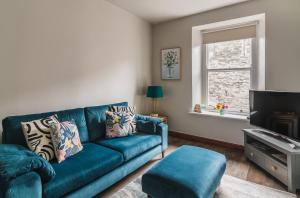 a living room with a blue couch and a window at Doodle Den in Kendal