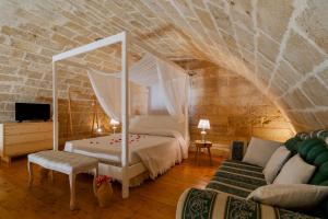 ein Schlafzimmer mit einem Himmelbett und einem Sofa in der Unterkunft Dimora Soleda in Torre San Giovanni Ugento